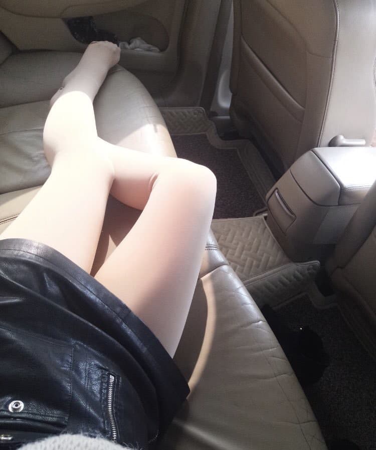 Intimate close-up of nylon-clad ankles under running water, sheer pantyhose clinging to skin with soft reflections and warm lighting.